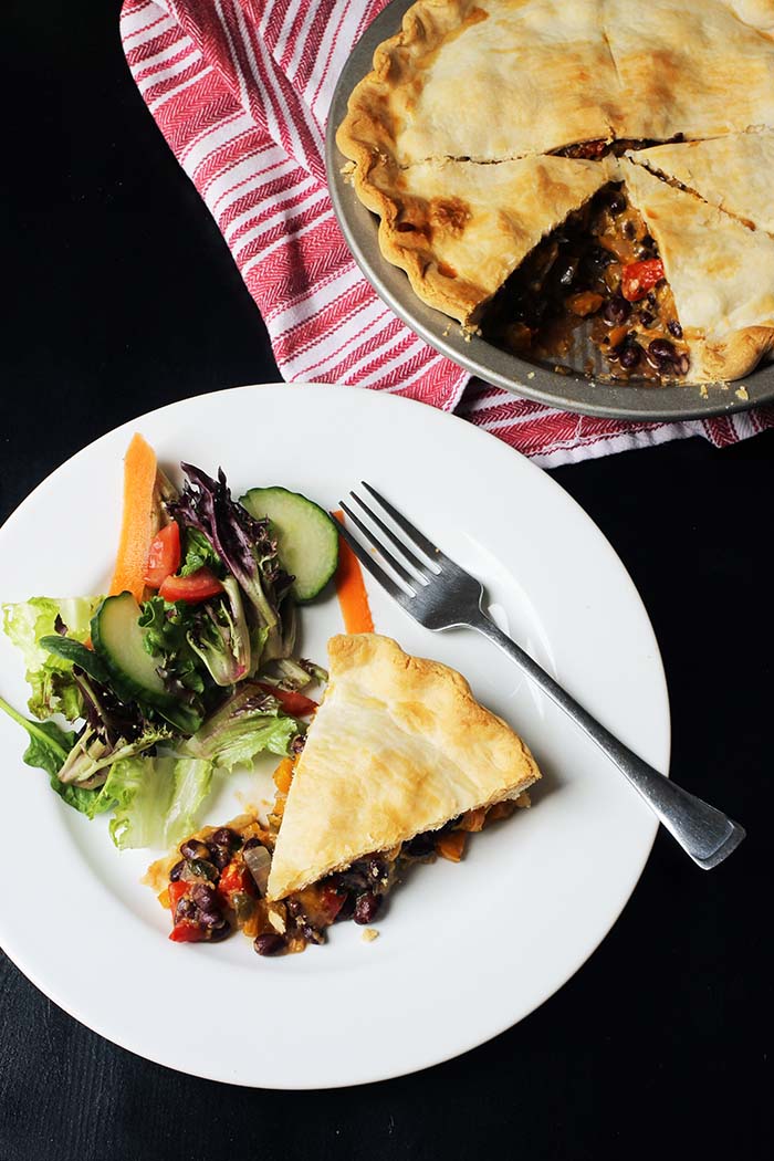 slice of black bean pie on plate next to pie plate