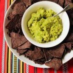 bowl of guacamole surrounded by blue corn tortillas