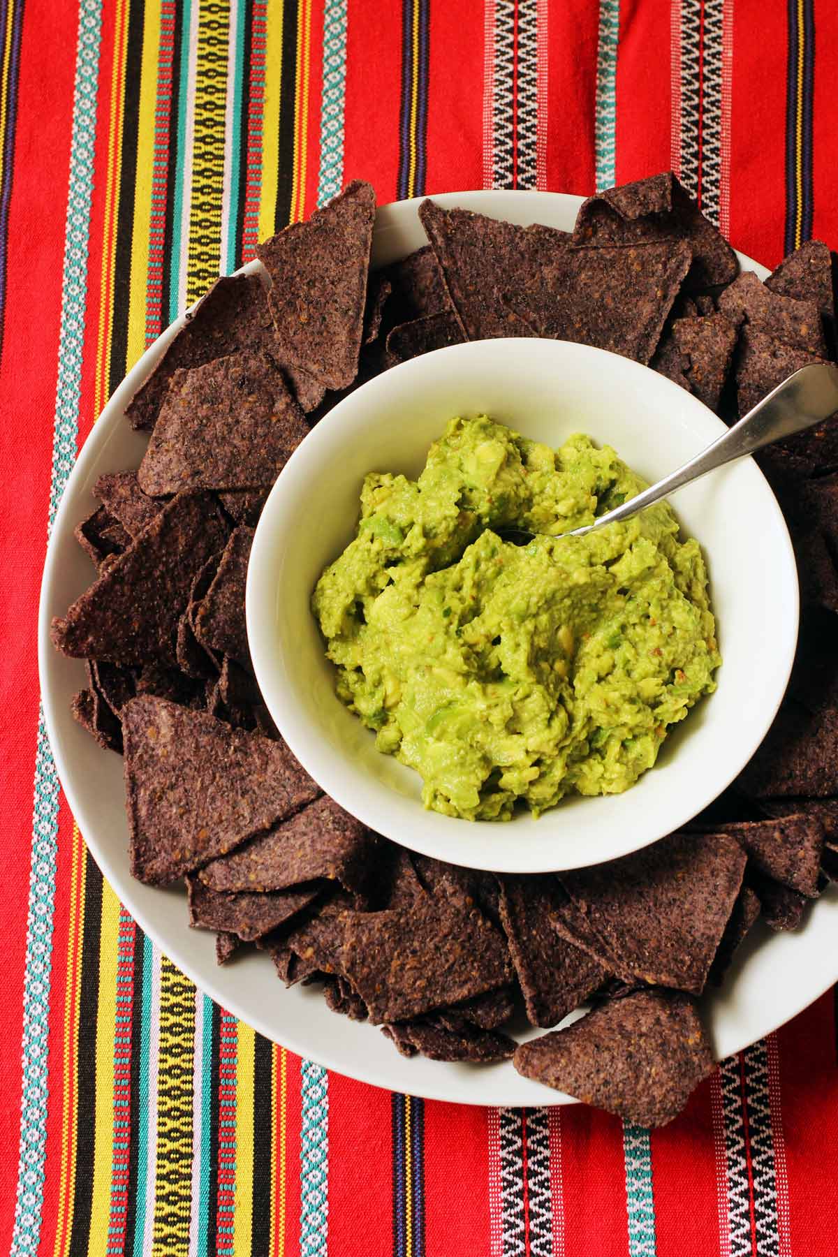 platter of blue corn chips with a bowl of guacamole in the center