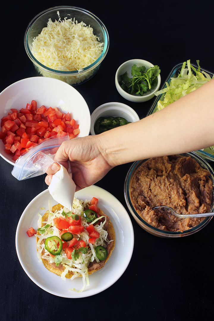 squeezing bag of sour cream on tostada