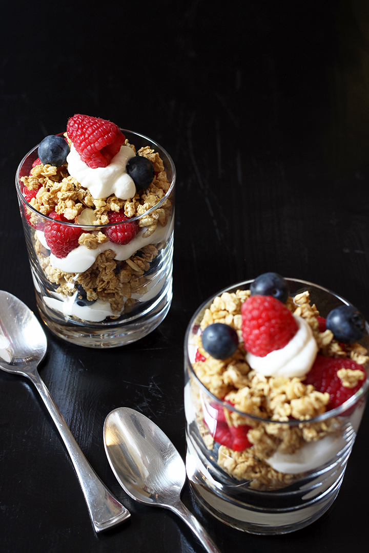 two yogurt parfaits on table with two spoons