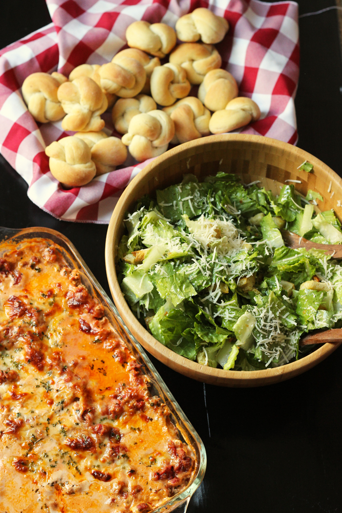 garlic knots, lasagna, and caesar salad in a bowl