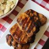 stack of balsamic pork chops on platter on red check cloth