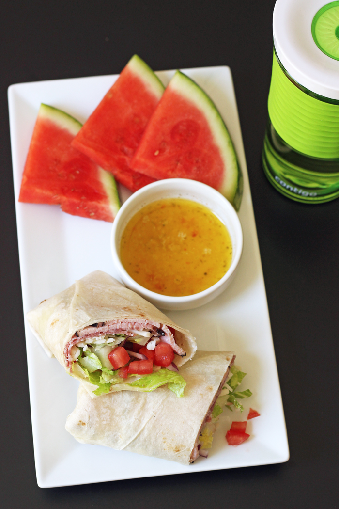 italian wrap with italian dressing and a side of a watermelon