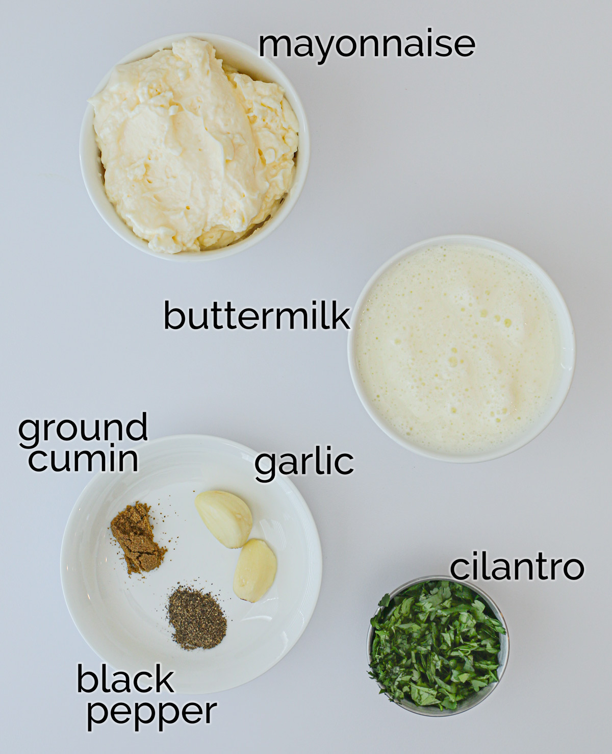 ingredients for creamy garlic dressing laid out on a white counter.