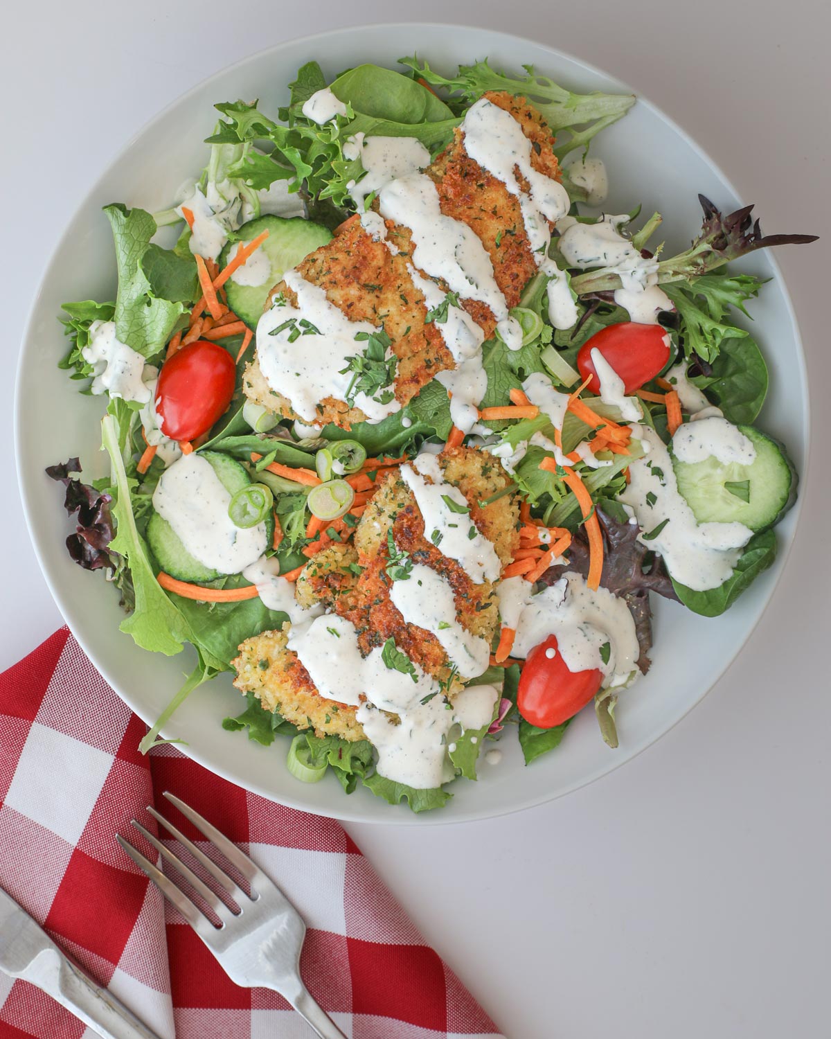 large green salad with creamy garlic dressing drizzled over the top.