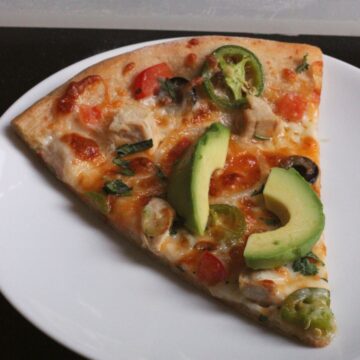 close up of a slice of jalapeño pizza on a plate.
