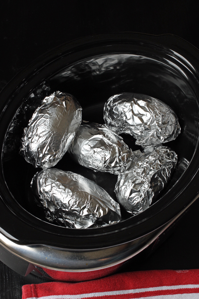 Foil wrapped baked potatoes in a slow cooker