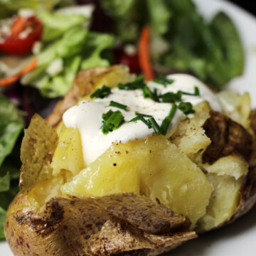 baked potato with toppings on plate with salad