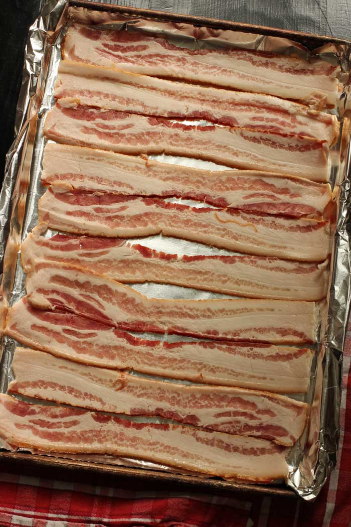 uncooked bacon on lined tray