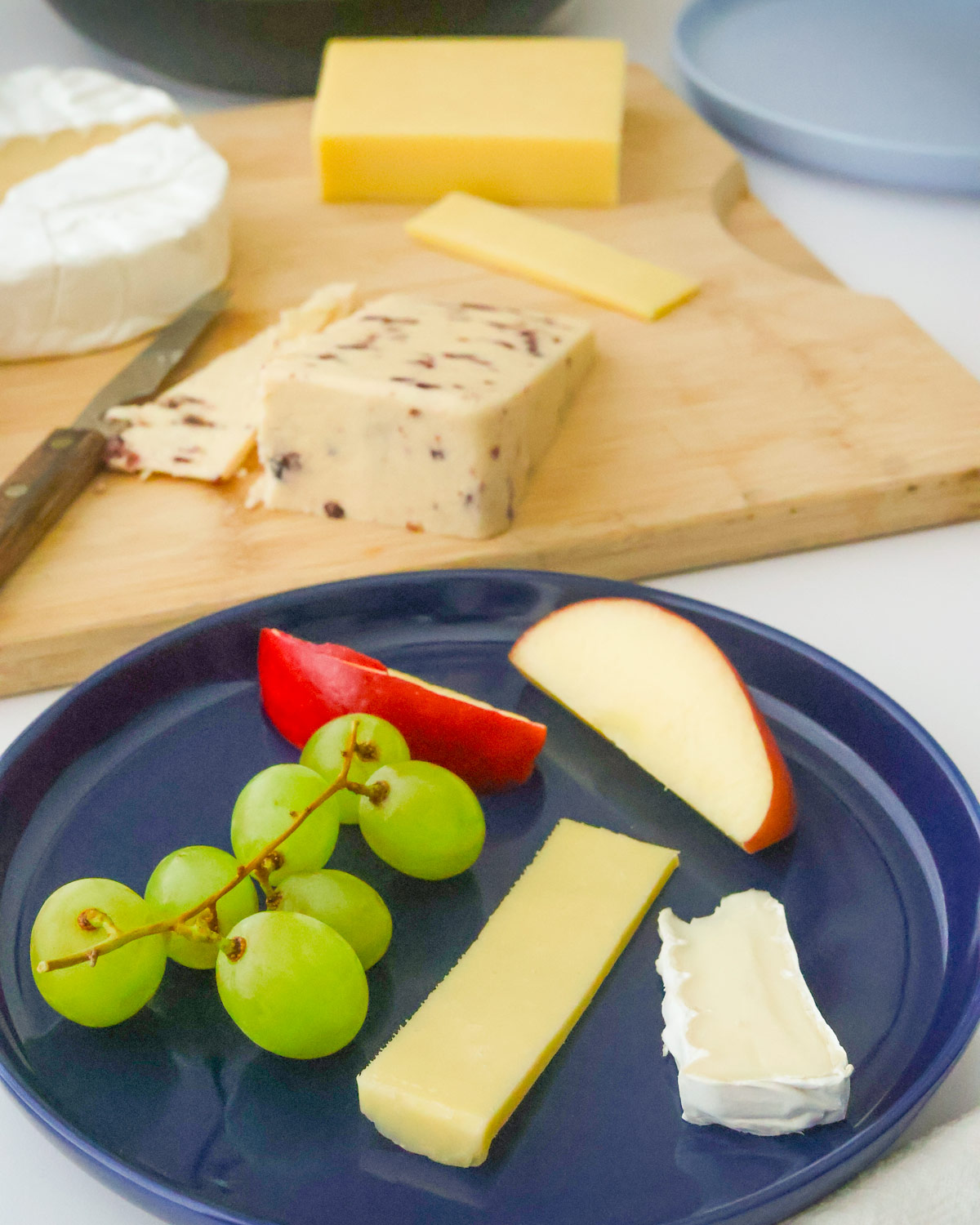 diner's plate with two cheese and two types of fruit on the plate.