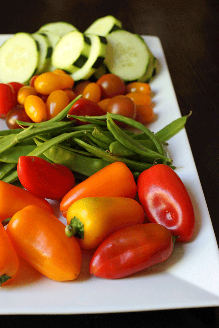 veggie tray with peppers, peas, tomatoes, and cokes