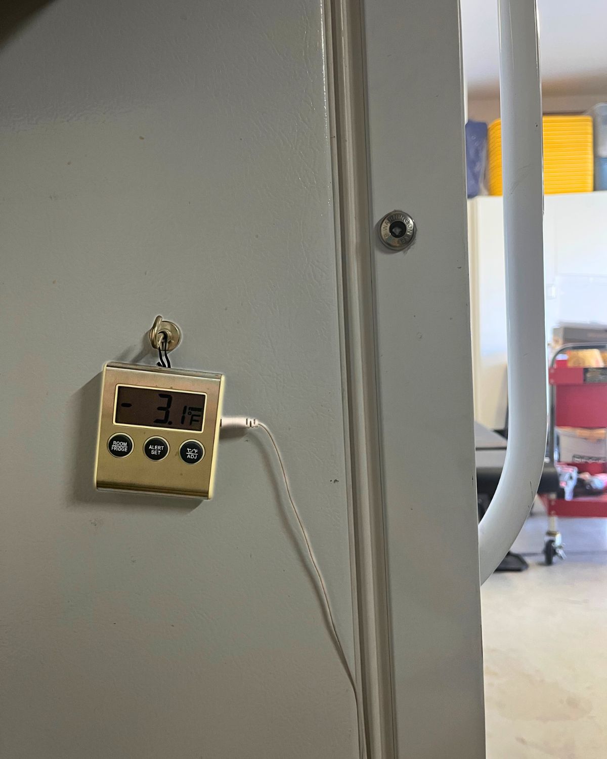 freezer alarm hanging on freezer exterior.