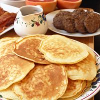 plate of pancakes on breakfast table with other breakfast foods