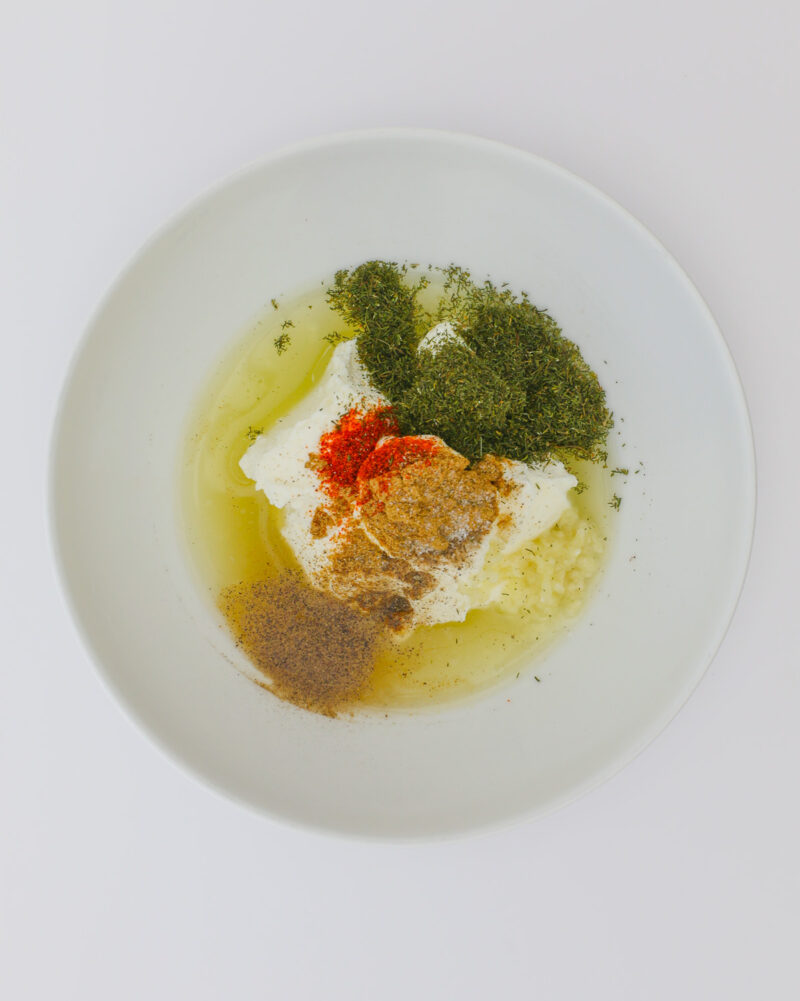 spices, yogurt, herbs, and lemon juice in white bowl.