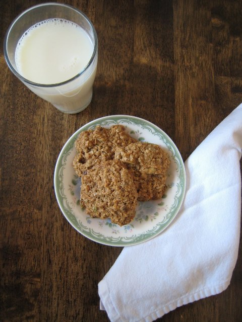 A cup of milk on table with plate of cookies