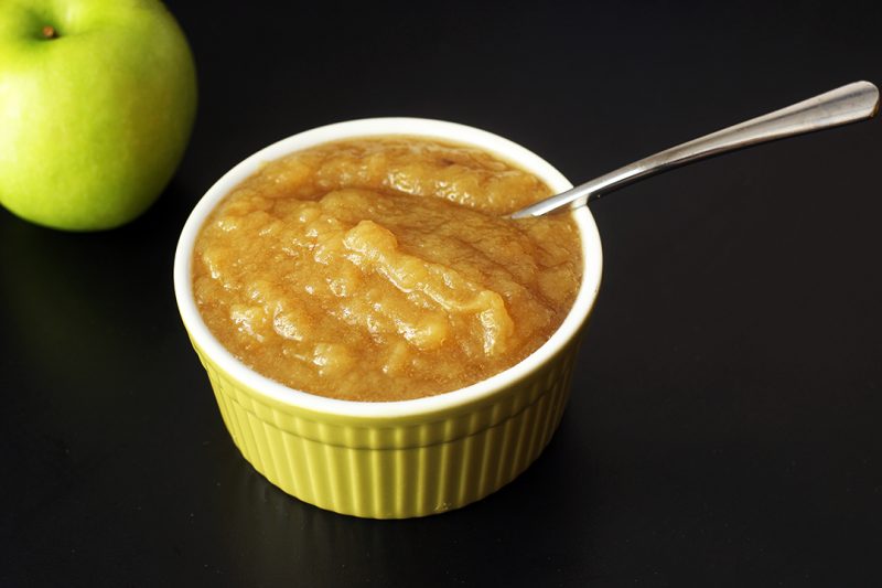 apple next to green bowl of applesauce with spoon