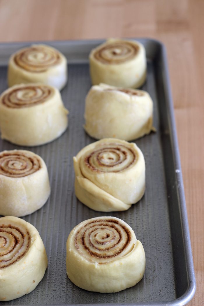 unbaked cinnamon rolls on open tray on counter