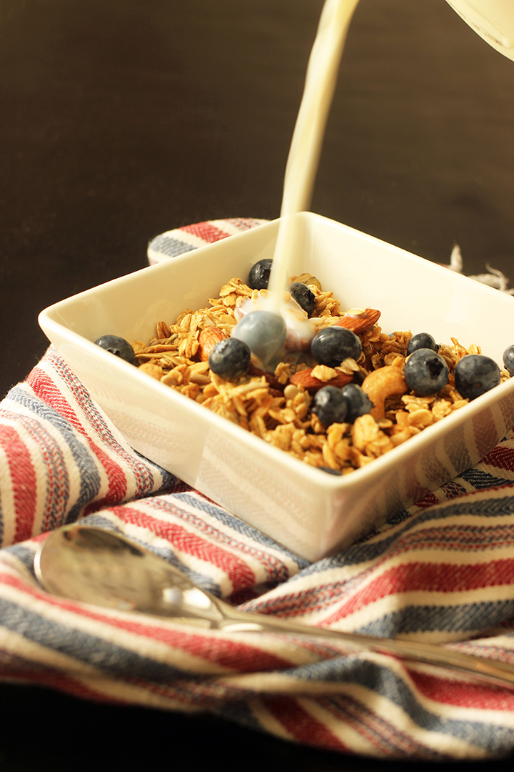 pouring milk into a bowl of maple granola