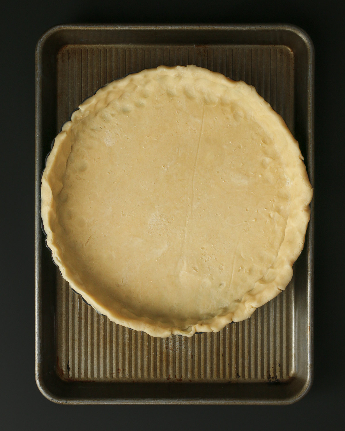 quiche pan with crust in a rimmed sheet pan.