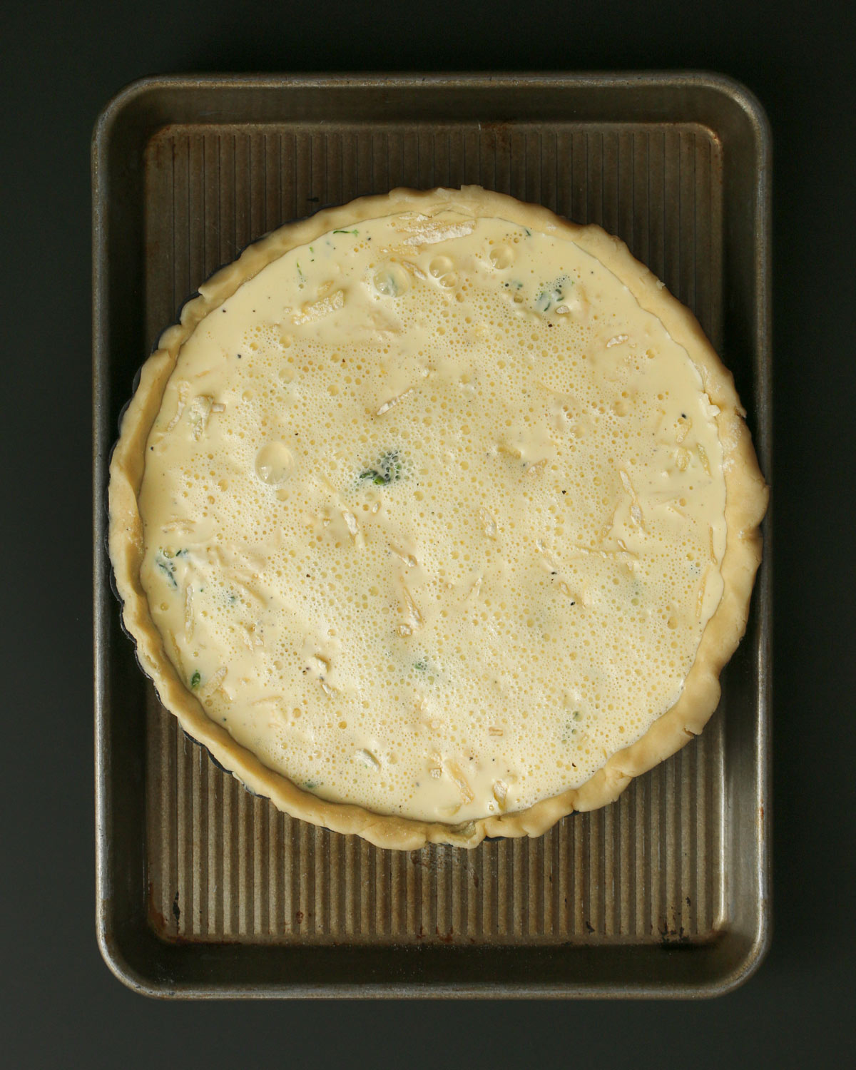 custard poured over spinach and cheese in quiche.