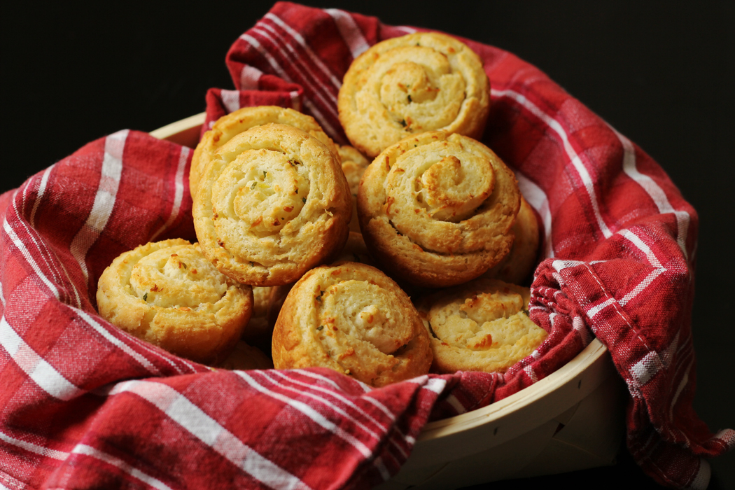 A basket of garlic parmesan swirl biscuits with a red cloth.