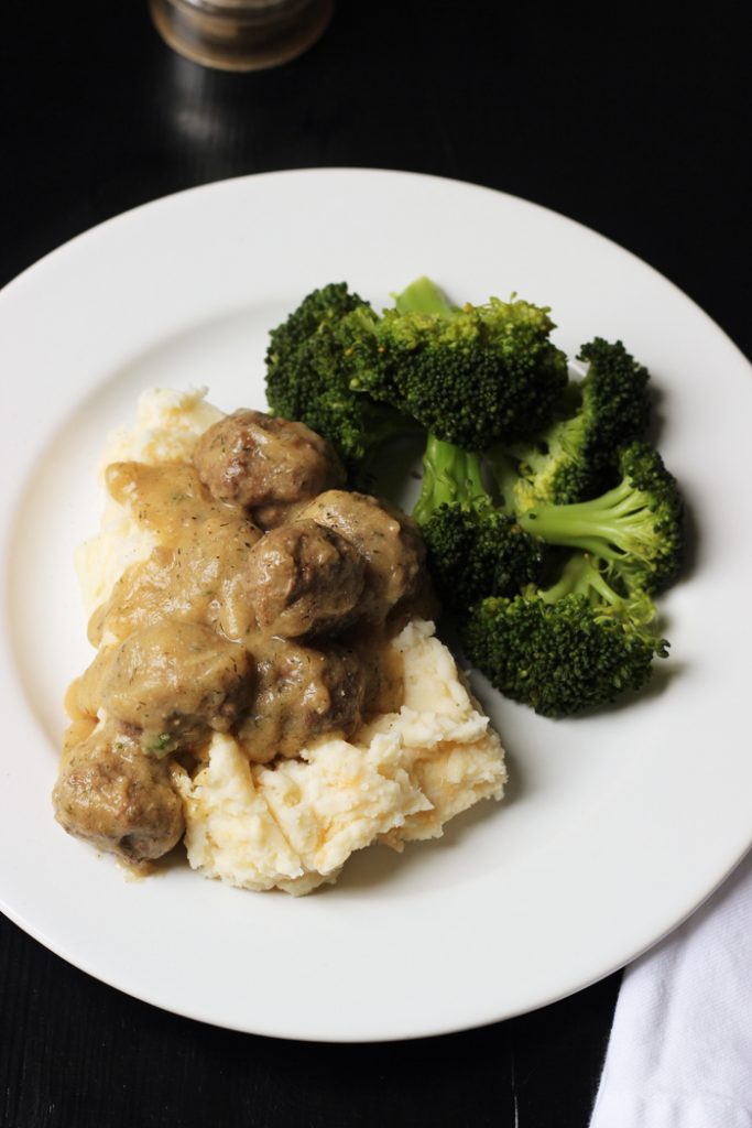 A plate of meatballs, mashed potatoes, and broccoli