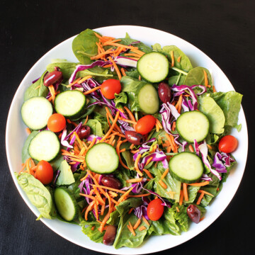 salad piled with cucumbers tomatoes olives and carrots