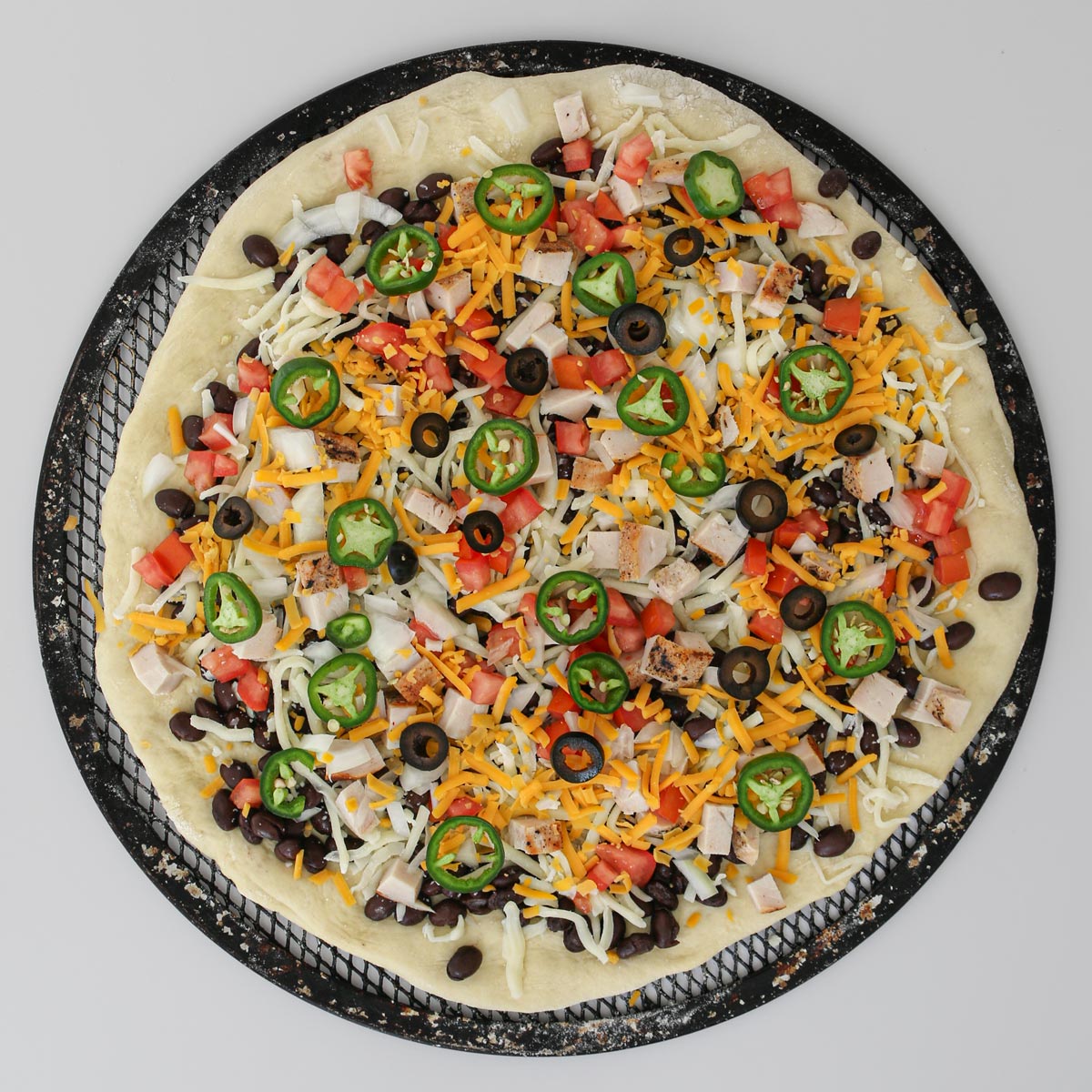 more cheese, olives, and jalapenos added to the pizza along with cooked chicken.