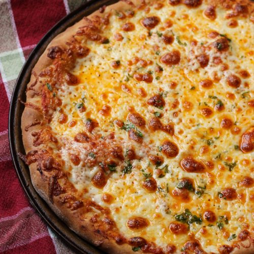 A pizza sitting on top of a pan on a table, with Cheese