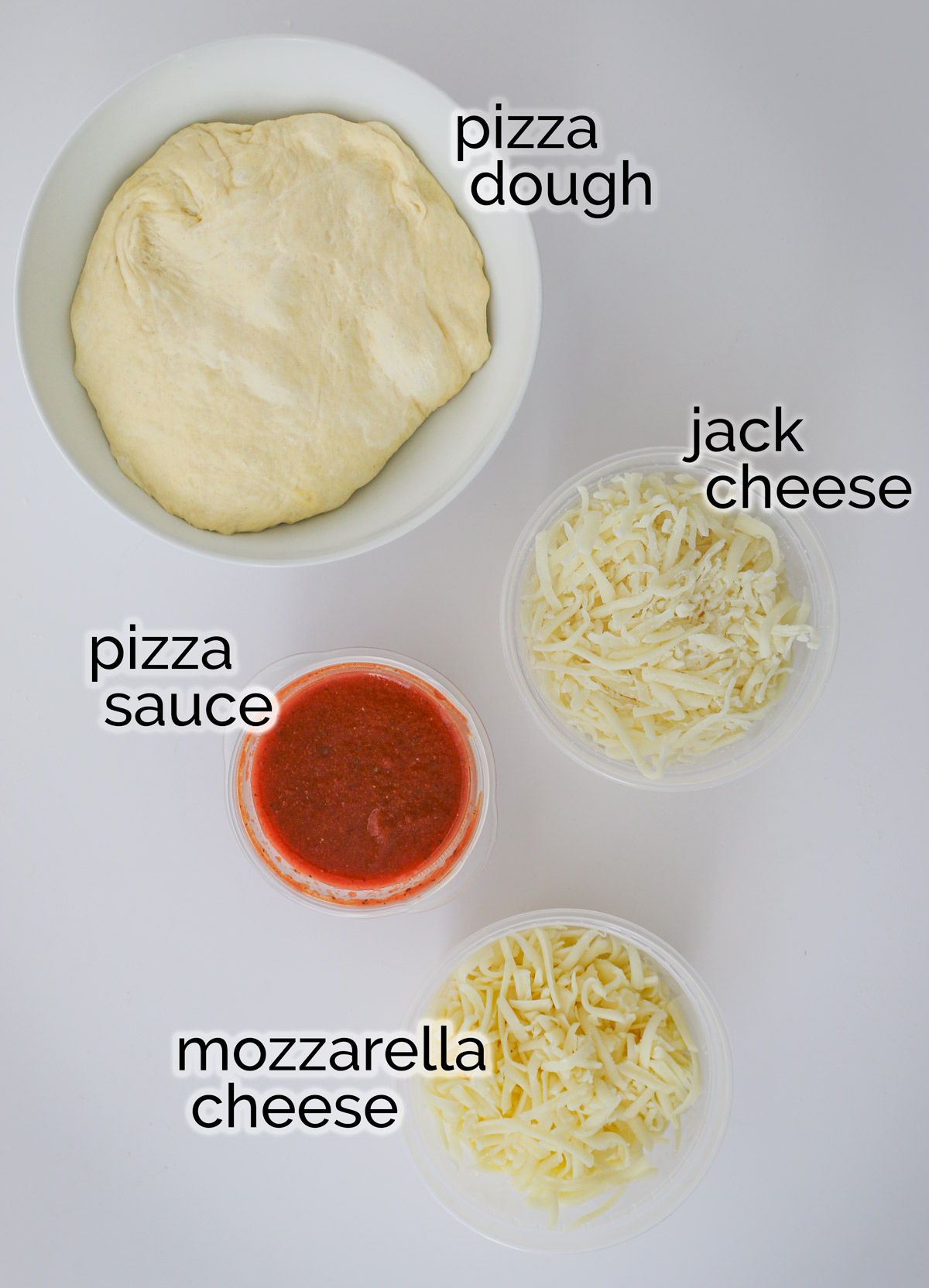 ingredients for cheese pizza laid out on a table.