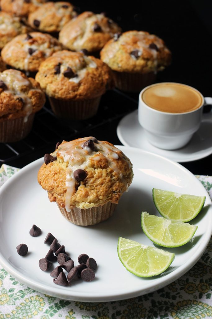 chocolate chip muffin on plate on table next to cooling rack with espresso