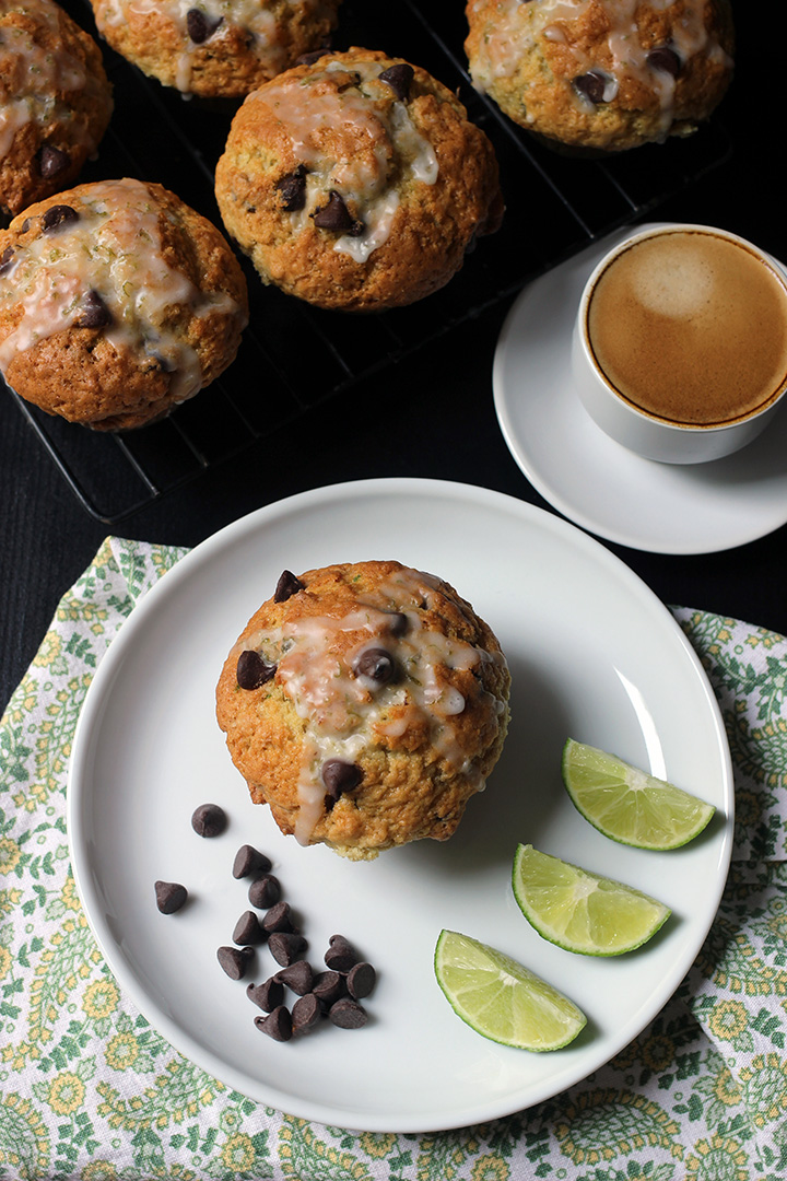 rack of muffins next to a plate with a muffin, chocolate chips, and lime wedges