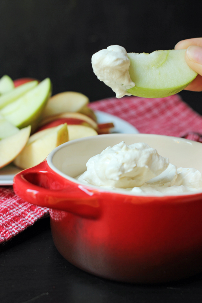 red dish of maple whipped cream with apple slice dipped