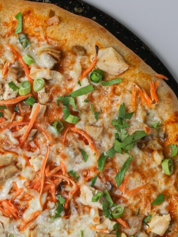 close up of unsliced Thai chicken pizza.