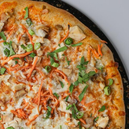 close up of unsliced Thai chicken pizza.