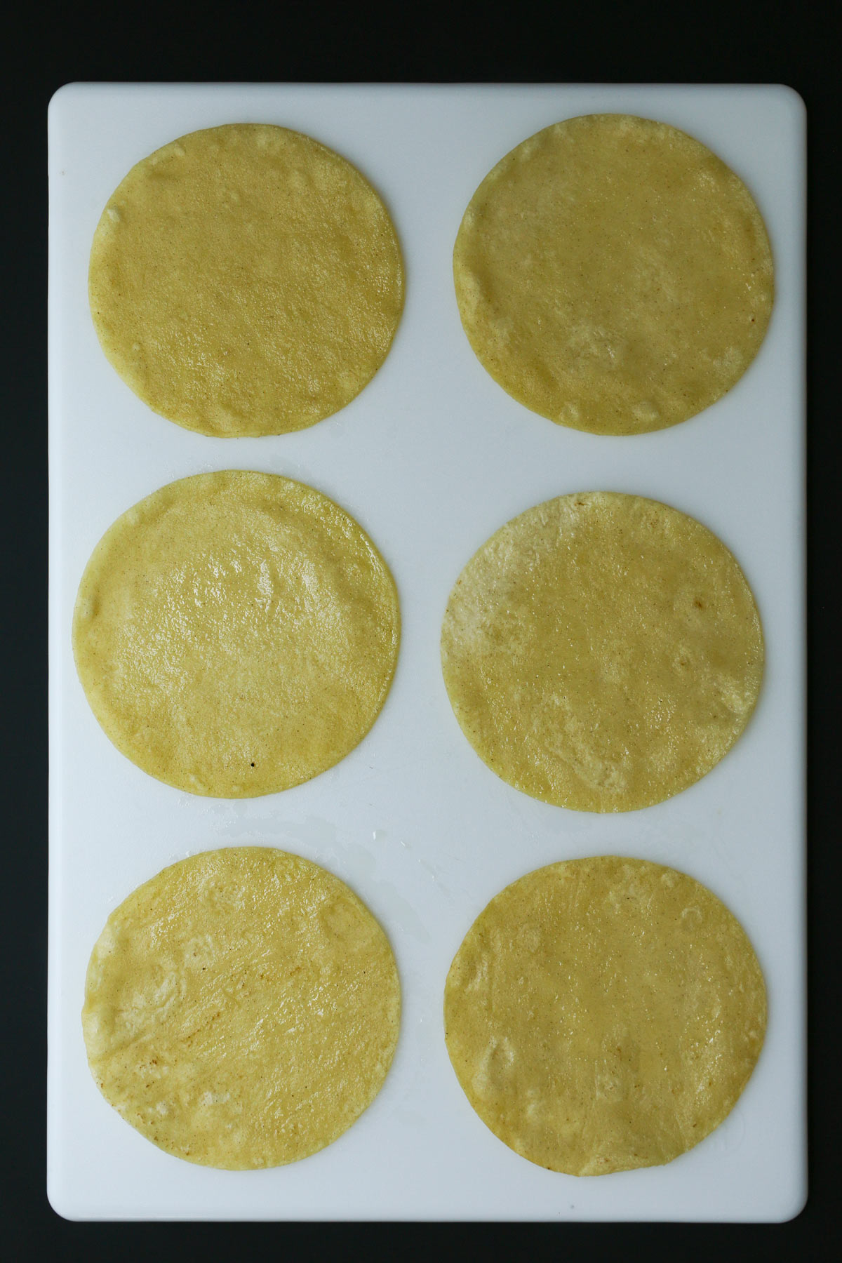six tortillas laid out on a white board.