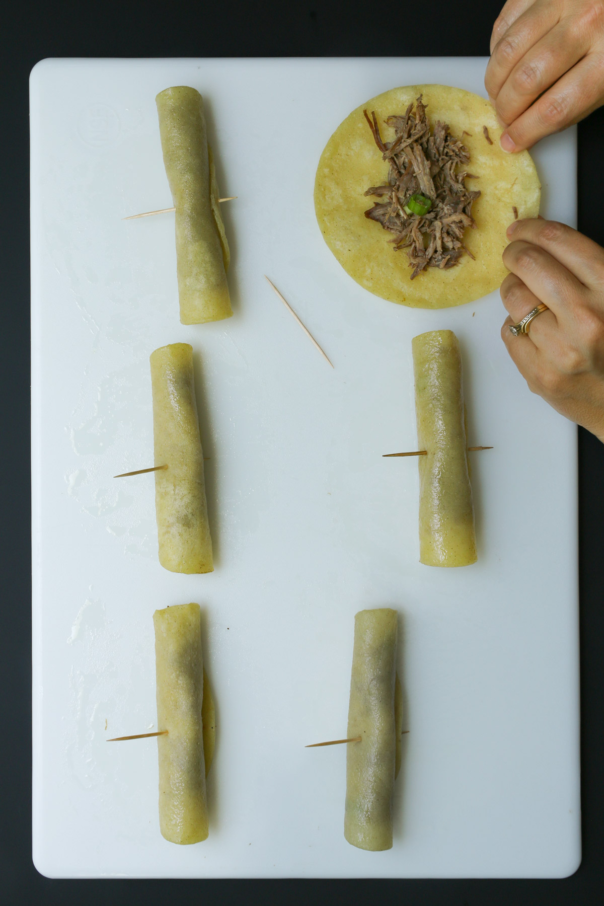 rolling taquitos with beef filling and securing with toothpicks.