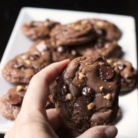 hand holding chocolate cookie in front of platter