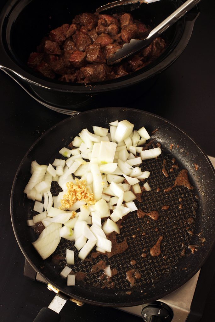 sauteeing onion and garlic in skillet next to crockpot