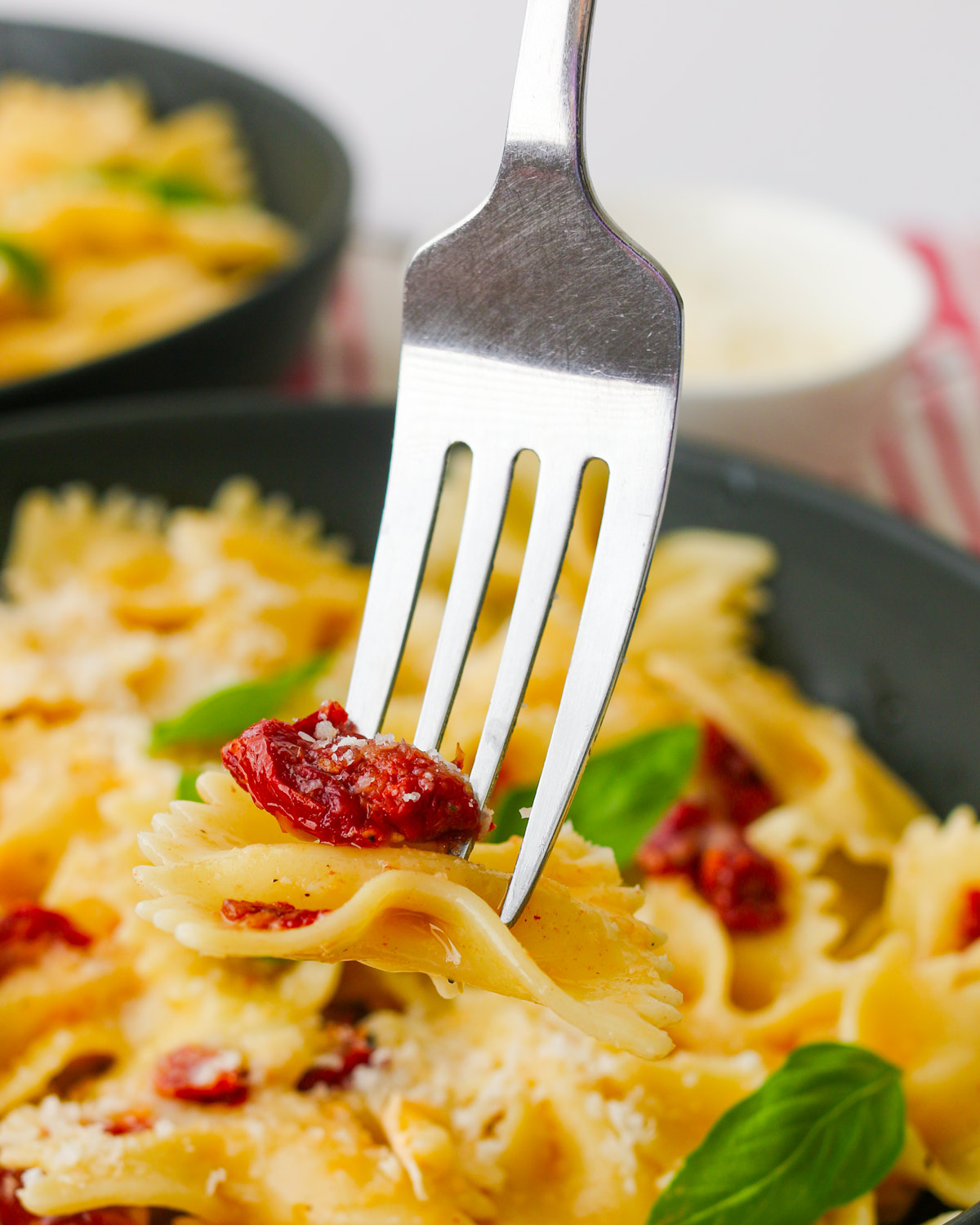 fork piercing a bite of brie and tomato pasta in a bowl.