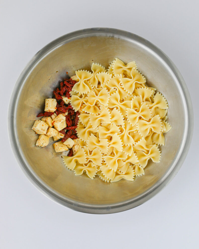 adding the hot pasta to the bowl.