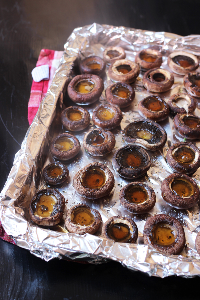broiled mushrooms caps on foil-lined tray filled with liquid to drain