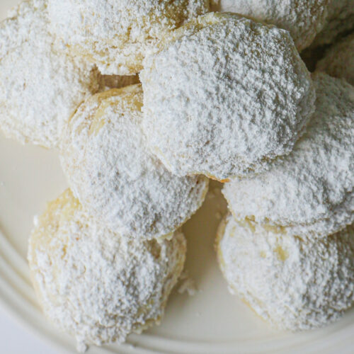 stack of snowball cookies on white plate.
