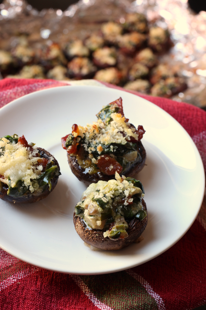 three stuffed mushrooms on plate with platter of mushrooms in background