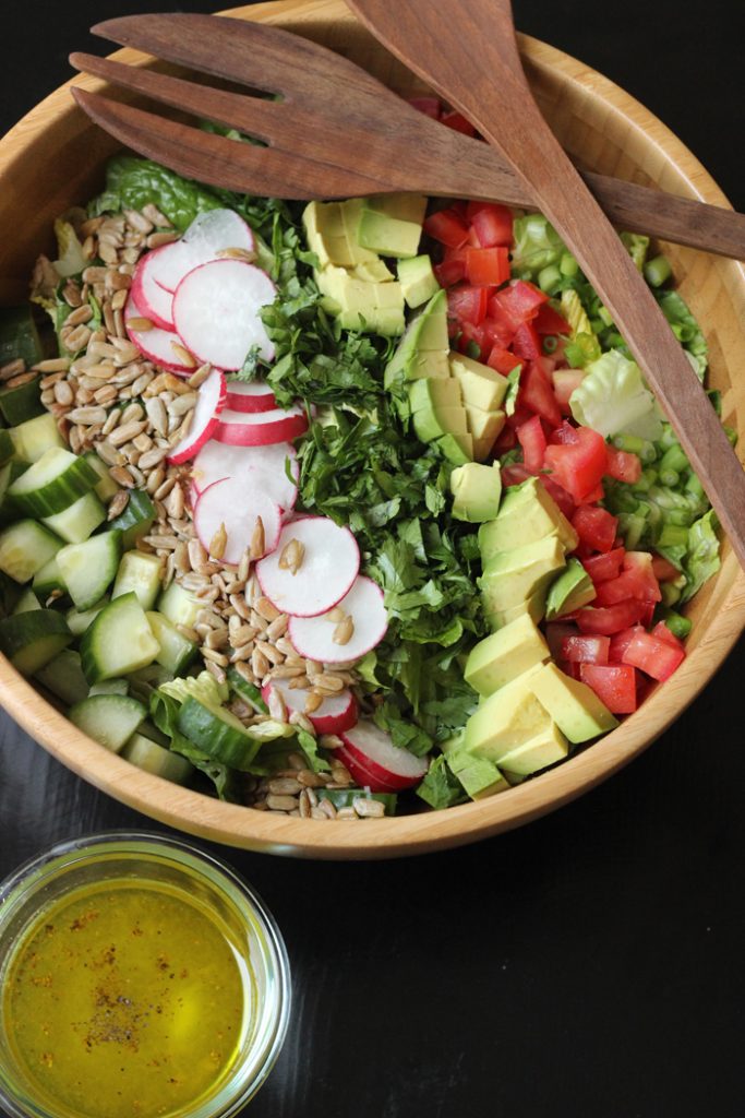 A bowl of chopped salad with radish and avocado