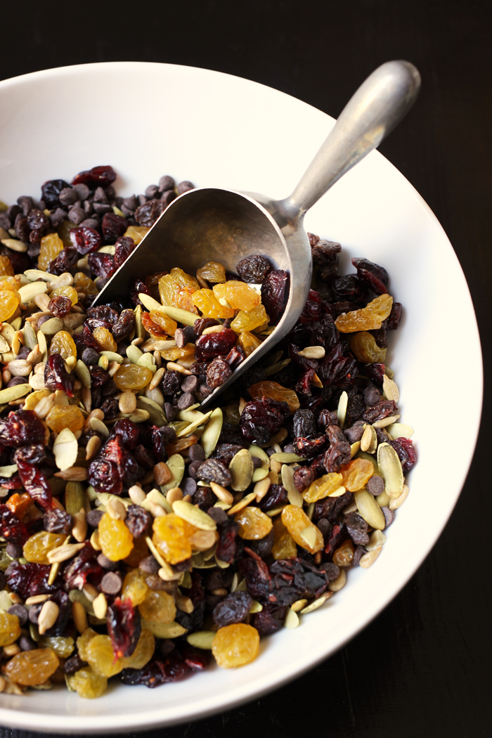 A bowl of trail mix with metal scoop