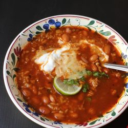 bowl of bean soup with sour cream cheese and lime
