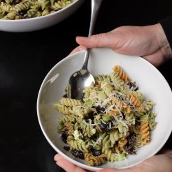 hands holiding bowl of Pesto Cranberry Pasta Salad