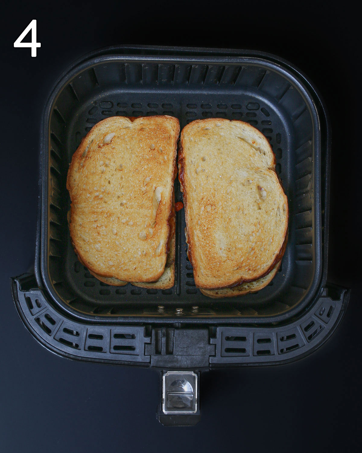 two air fryer grilled cheese sandwiches in air fryer basket.